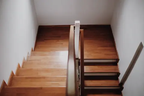 Een houten trap in een lichte hal.