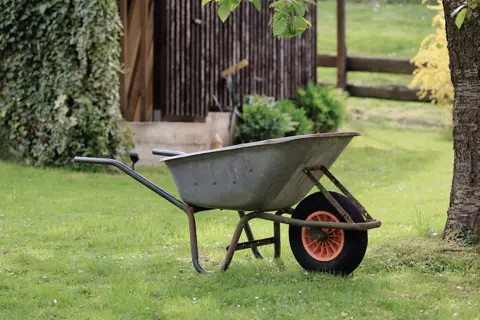 Een kruiwagen op het gras in een tuin.